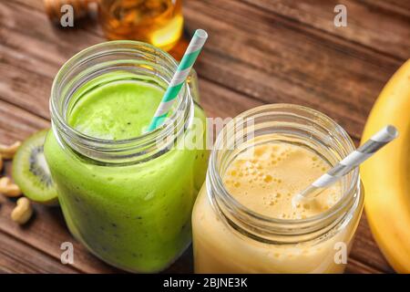 Jars with tasty protein shakes on wooden table, closeup Stock Photo