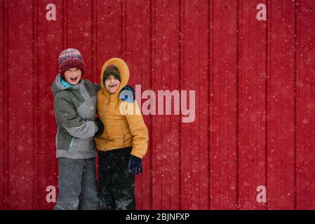 Two happy children messing about in front of a red house, USA Stock Photo