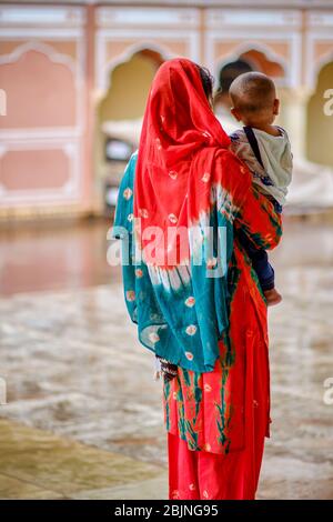 Young Rajasthani Indian woman in colorful traditional sari holding a baby in Jaipur (Pink city), Rajasthan, India Stock Photo