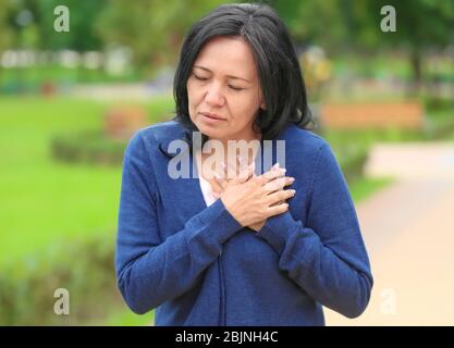 Mature woman suffering from heart attack outdoors Stock Photo