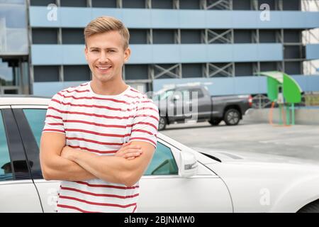Handsome young man standing near car outdoors Stock Photo