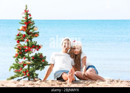 Young couple and Christmas tree on beach Stock Photo