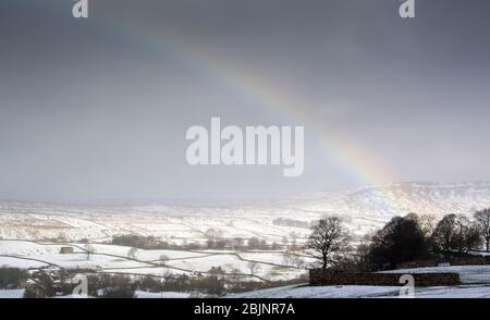 Rainbow over Wensleydale in a snow shower. North Yorkshire, UK. Stock Photo