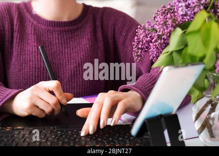 Graphic Designer retoucher freelancer works from home. Woman draws on graphic tablet in cozy home office using laptop, computer. Remote work. Blogger Stock Photo