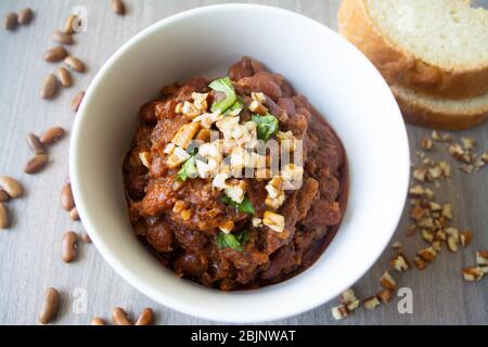 Traditional Georgian vegan kidney beam stew lobio with chopped walnuts and parsley served in a bowl with slices of bread Stock Photo