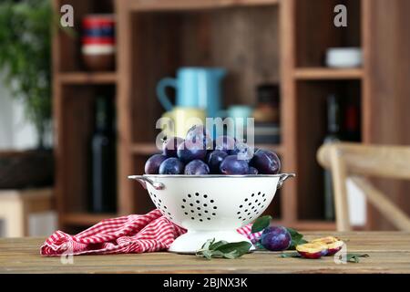 Fresh plums in colander on table Stock Photo