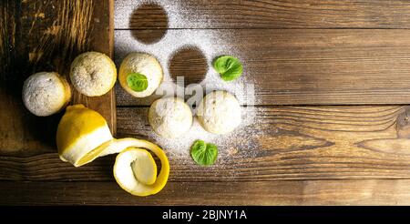 Muffins with lemon and mint on gray plate on dark wooden table. Top views with clear space Stock Photo