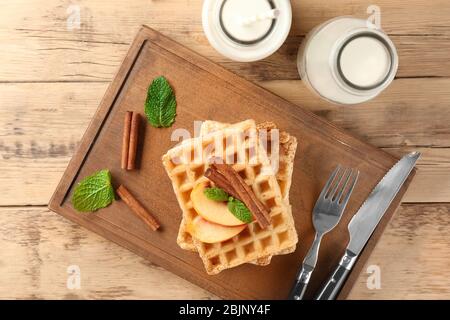 Delicious cinnamon waffles on wooden board Stock Photo