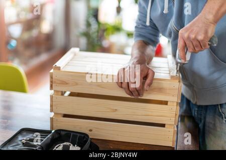 Man drilling wooden crate with power tool at home Stock Photo
