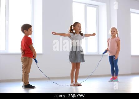 Adorable children skipping rope indoors Stock Photo