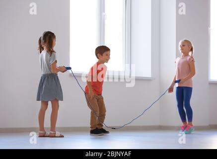 Adorable children skipping rope indoors Stock Photo