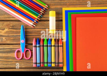 Composition with color paper, pencils and crayons on wooden background Stock Photo