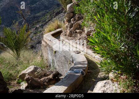Traditional falaj irrigation channel at hillside above Wakan village, Oman Stock Photo