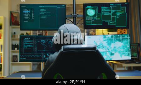 Hacker wearing a hoodie while committing cyber crimes from his apartment. Stock Photo
