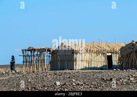 Afar woman standing in front of a traditional shelter of Afar nomads, Danakil Depression, Afar Province, Ethiopia Stock Photo