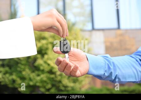 Saleswoman giving car key to customer outdoors Stock Photo