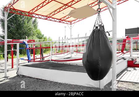 Punching bag near boxing ring prepared for competition, outdoors Stock Photo