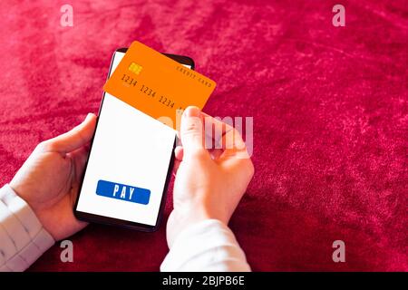 Human hand holding smartphone with online shopping app and credit card. Stock Photo