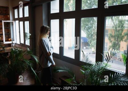 Young woman looking through the window Stock Photo