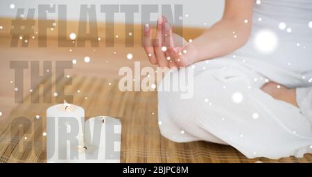 Caucasian woman practising yoga with words #Flatten the curve during coronavirus covid19 pandemic Stock Photo