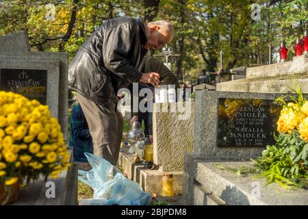 Family members light candles and put them on a grave at the Rakowicki cemetery in Krakow, Poland 2019. Stock Photo