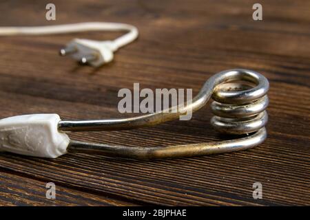 Old immersion water heater on dark wooden background. Close-up Stock Photo