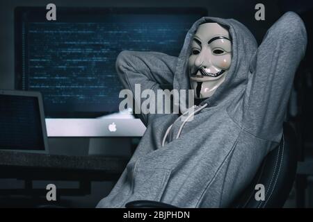MYKOLAIV, UKRAINE - SEPTEMBER 29, 2017: Anonymous person in Guy Fawkes mask near computer indoors Stock Photo