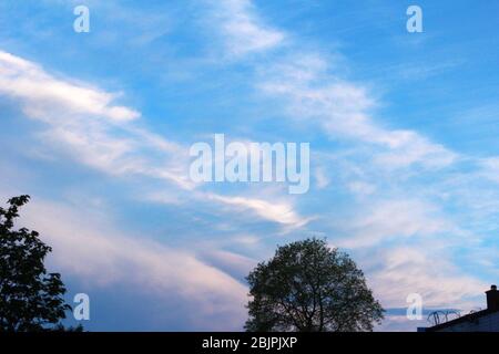 Pale pink clouds in a bright blue sky in Manchester, England Stock Photo