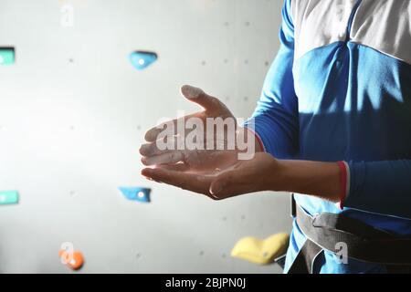 Young man applying talc powder on hands in climbing gym Stock Photo