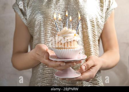 Woman holding delicious cupcake with candles Stock Photo