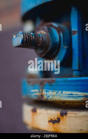Old industrial screw nut rust on a blue pipe. Selective focus, macro photography Stock Photo
