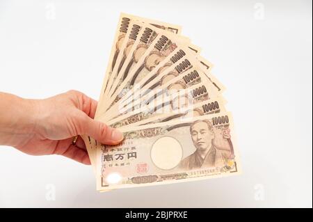Hand holding 100,000 yen. Isolated on white background. Copy space. Horizontal shot. Stock Photo