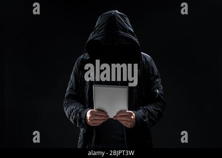 Hacker with tablet on dark background Stock Photo