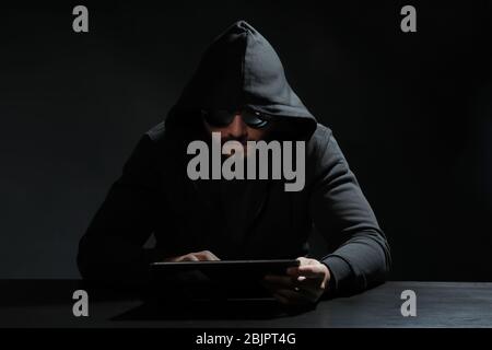 Hacker using tablet on dark background Stock Photo
