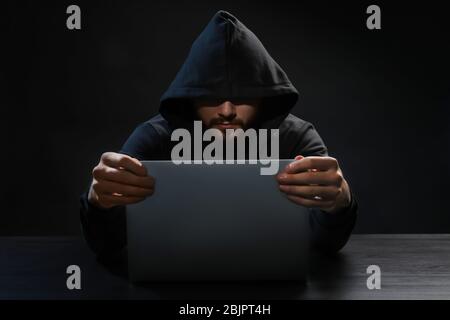 Hacker using laptop on dark background Stock Photo