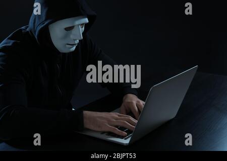 Hacker using laptop on dark background Stock Photo