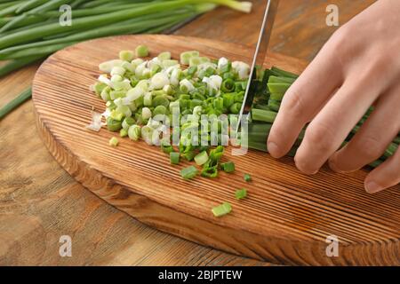 https://l450v.alamy.com/450v/2bjptew/woman-cutting-fresh-green-onion-on-wooden-table-2bjptew.jpg