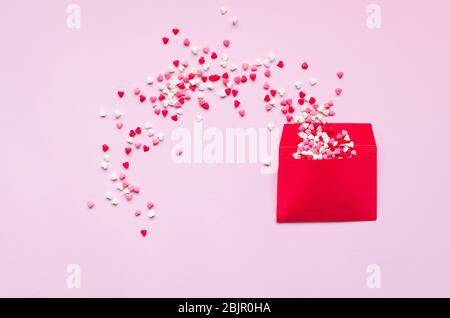 Opened red envelope and many felt hearts on pink background with place for text. Love letter mail correspondence relationship. Valentines day concept. Stock Photo