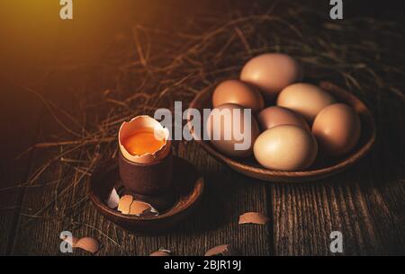 Still life of cracked raw farm egg on vintage wooden background Stock Photo