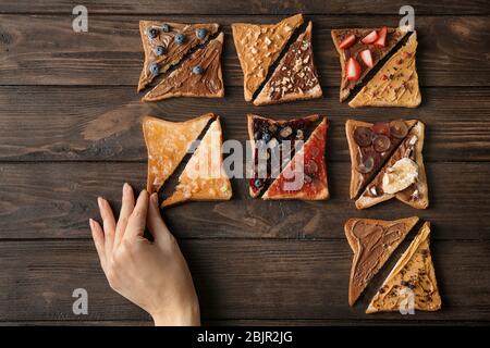 Woman holding one of fresh crispy toasts on wooden table Stock Photo