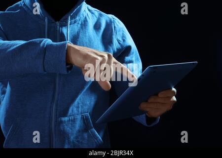 Professional hacker with tablet on dark background Stock Photo