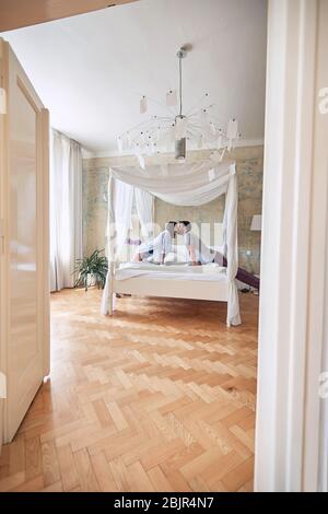 Loving young man and woman kissing in the morning while making the bed. Stock Photo