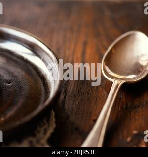 Atmospheric  Closeup of shiny silver spoon on wooden table set with round empty brown bowl before meal shot for copy space in background Stock Photo