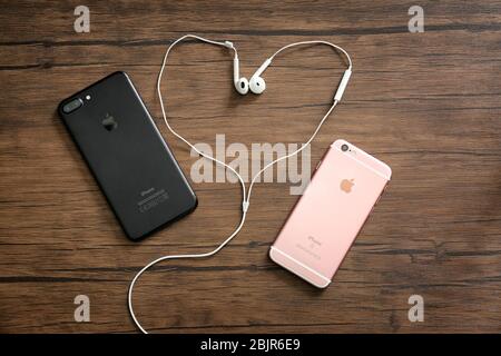 KYIV, UKRAINE - OCTOBER 24, 2017: iPhone 7 Plus Black and iPhone 6S Rose Gold with earphones on wooden background Stock Photo