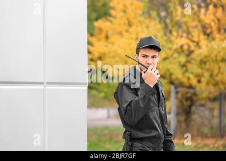 Male security guard using portable radio transmitter outdoors Stock Photo