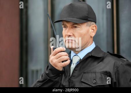 Male security guard using portable radio outdoors Stock Photo