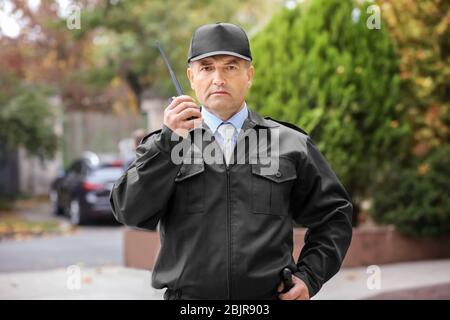Male security guard using portable radio outdoors Stock Photo