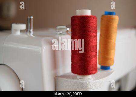 colored thread coils mounted on a pin of a sewing machine Stock Photo