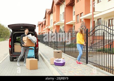Young couple unloading boxes from their car on moving day Stock Photo