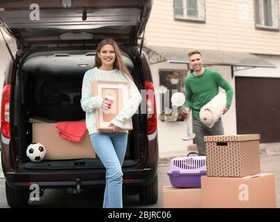 Young couple unloading boxes from their car on moving day Stock Photo